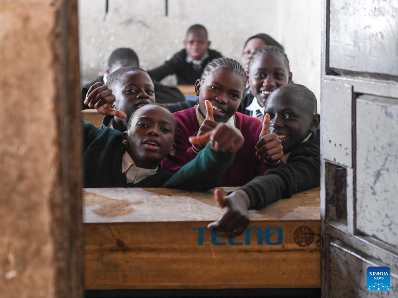 Wanafunzi wakionekana katika picha pamoja na madawati mapya yaliyochangiwa shuleni katika mitaa ya mabanda ya Mathare jijini Nairobi, Kenya, Oktoba 15, 2024. (Xinhua/Li Yahui)